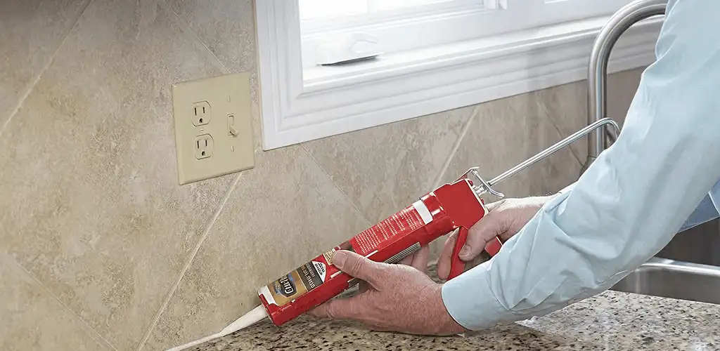 Handyman applying caulk along a kitchen backsplash and countertop seam in Yonkers, NY