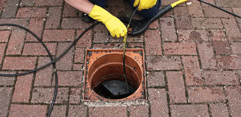 Drain cleaning technician using a drain snake to clear a clogged drain in Yonkers, NY