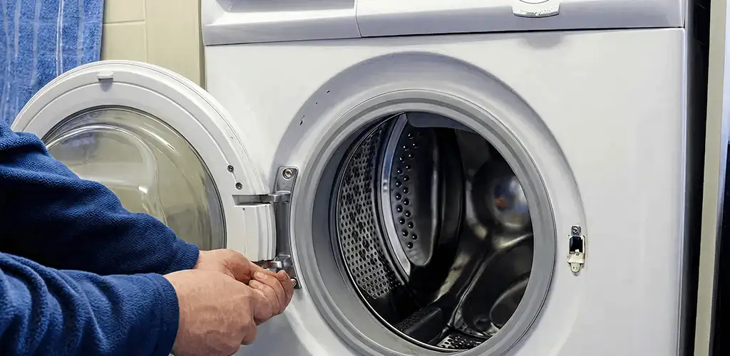 Washing machine repair handyman checking a front-load washer door and latch in Yonkers, NY