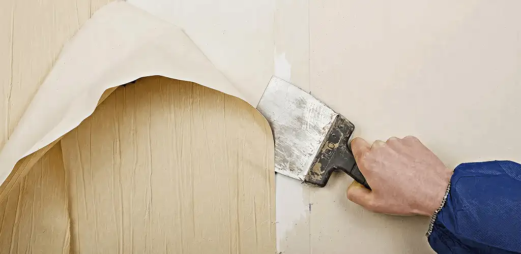 Handyman removing wallpaper with a scraper for wall preparation in Yonkers, NY