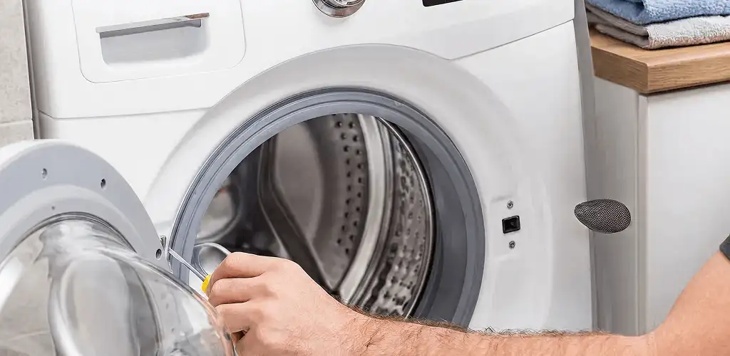Handyman repairing a front-load washing machine and inspecting the drum in Yonkers, NY