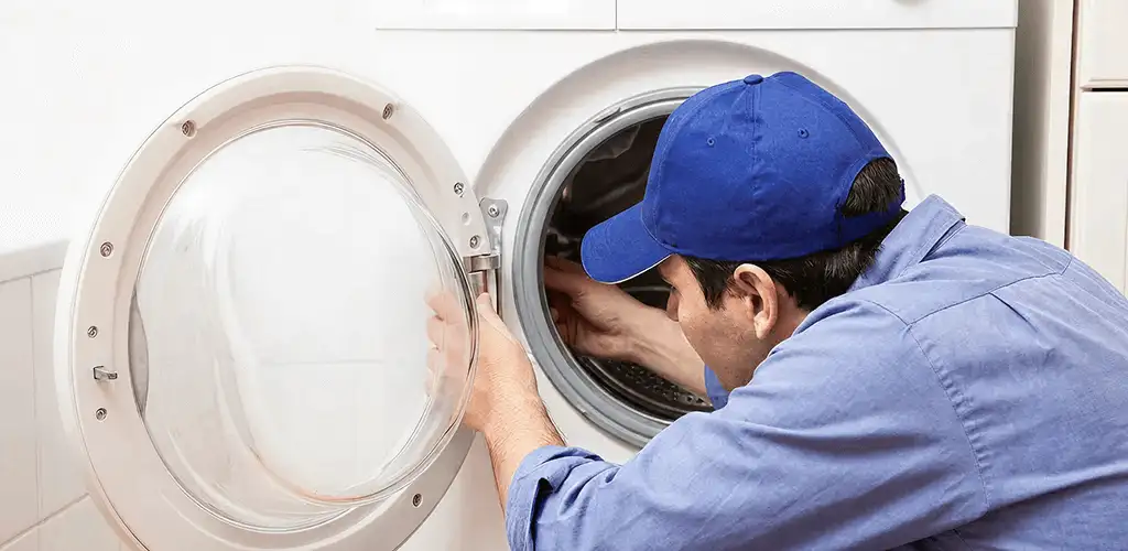Washing machine repair handyman inspecting a front-load washer drum in Yonkers, NY