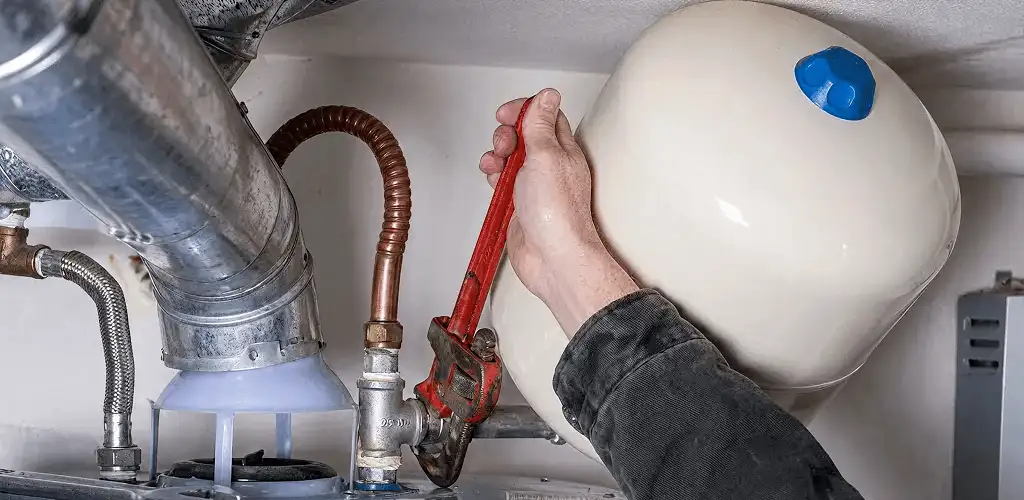 Water heater repair technician tightening plumbing connections near a tank unit in Yonkers, NY